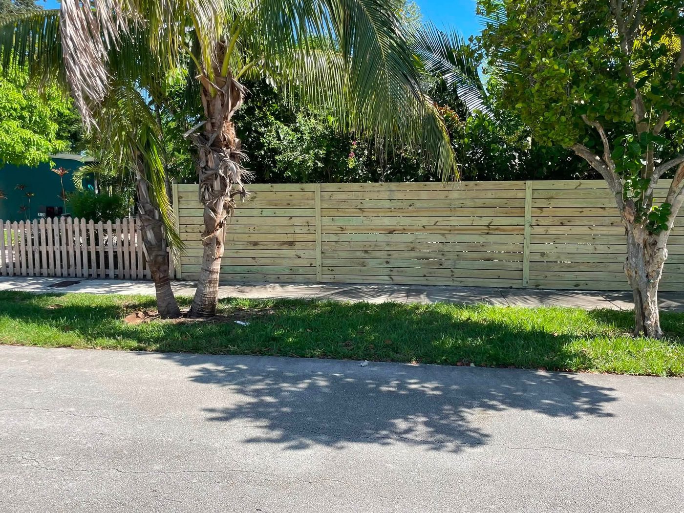 Completed horizontal wood privacy fence along a sidewalk