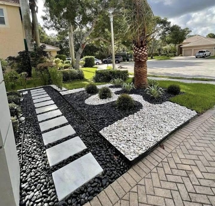 Completed black and white river rock landscape design with a stepping-stone path